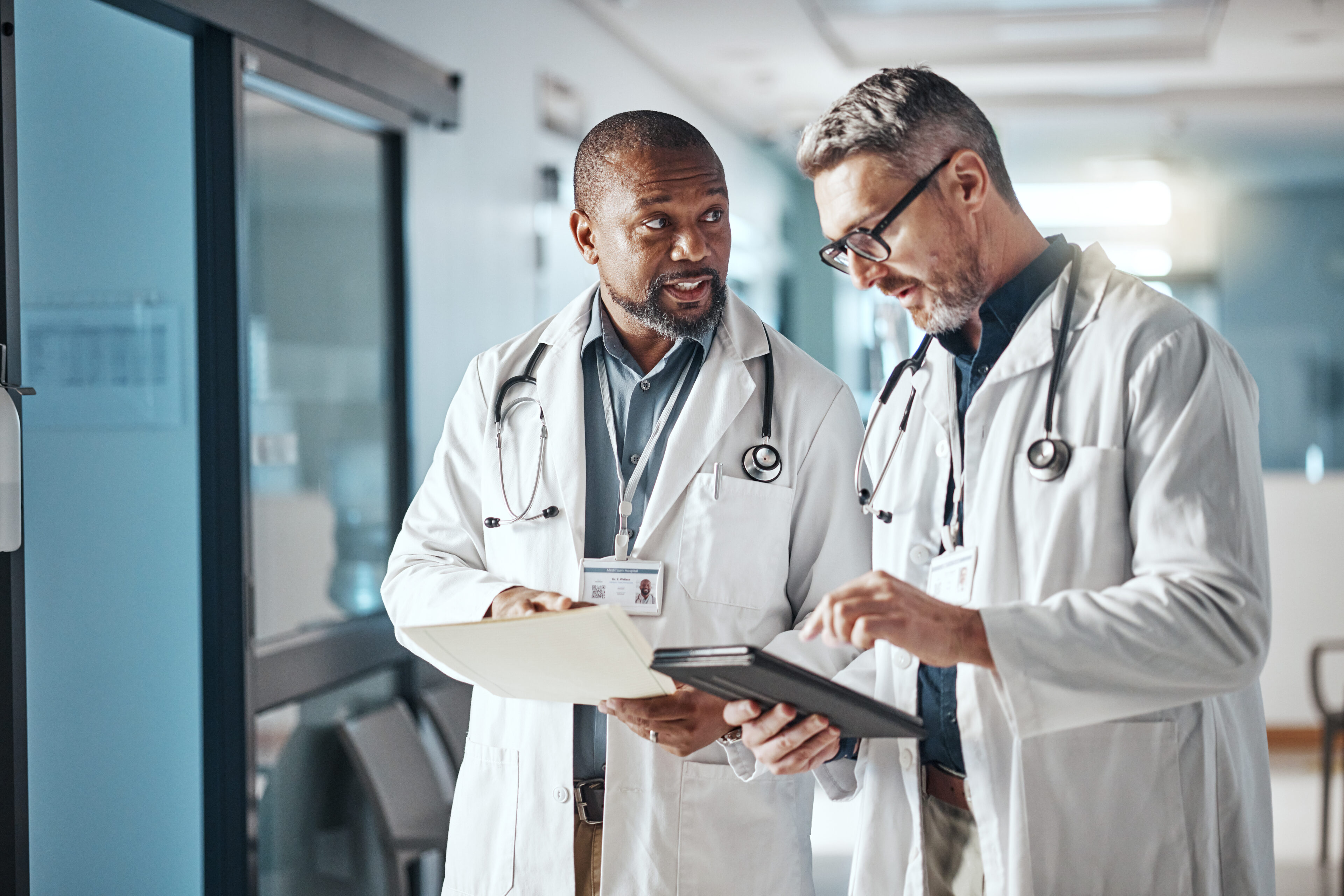 Doctors discussing patient files in hospital hallway.